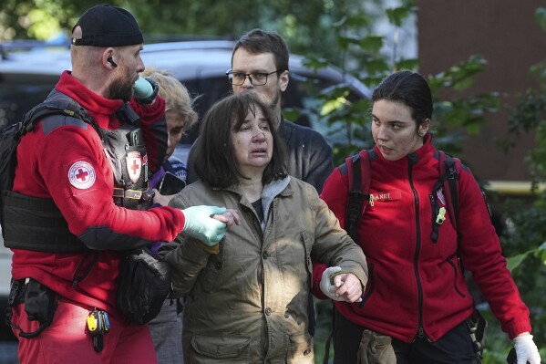 Medical workers help a woman in the yard of an apartment building destroyed after a Russian attack in Kyiv, Ukraine, early Monday, June 23, 2025. (AP Photo/Efrem Lukatsky)