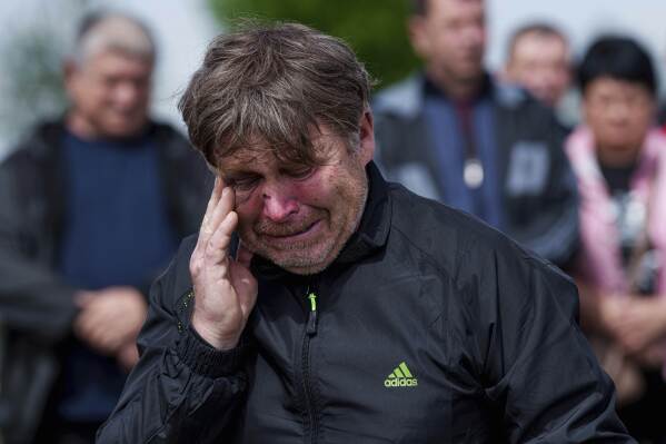 A father mourns his children Tamara Martyniuk, 8, Stanislav Martyniuk, 12, and Roman Martyniuk, 17, killed in a Russian strike on Sunday, during farewell ceremony in Korostyshiv, Zhytomyr region, Ukraine, Wednesday, May 28, 2025. (AP Photo/Evgeniy Maloletka)