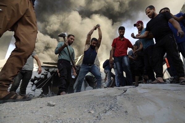 Palestinians strike the concrete while looking for survivors under the rubble of a destroyed house following an Israeli airstrike in Gaza City, Saturday, Nov. 4, 2023. (AP Photo/Abed Khaled)