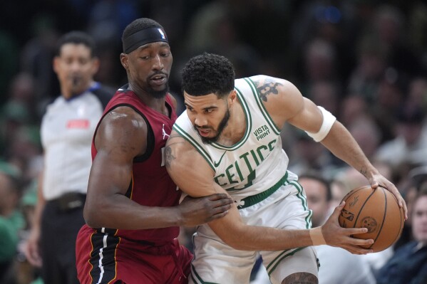 Miami Heat center Bam Adebayo, left, defends as Boston Celtics forward Jayson Tatum, right, drives toward the basket in the second half of Game 1 of an NBA basketball first-round playoff series, Sunday, April 21, 2024, in Boston. (AP Photo/Steven Senne)