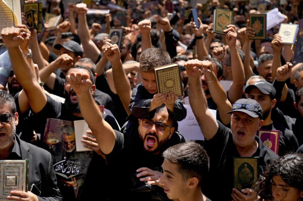 Hezbollah supporters chant slogans as they raise the Quran during a rally after Friday prayers in the southern Beirut suburb of Dahiyeh, Lebanon, Friday, July 21, 2023. Muslim-majority nations expressed outrage Friday at the desecration of the Islamic holy book in Sweden. Following midday prayers, thousands took to the streets to show their anger, in some cases answering the call of religious and political leaders. (AP Photo/Bilal Hussein)