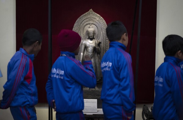 School children look at a statue of Lord Buddha stolen earlier from Nepal and brought back from New York's metropolitan museum of art, as the same is displayed at the National Museum in Kathmandu, Nepal, Jan. 3, 2024. An unknown number of sacred statues of Hindu deities were stolen and smuggled abroad in the past. Now dozens are being repatriated to the Himalayan nation, part of a growing global effort to return such items to countries in Asia, Africa and elsewhere. (AP Photo/Niranjan Shrestha)