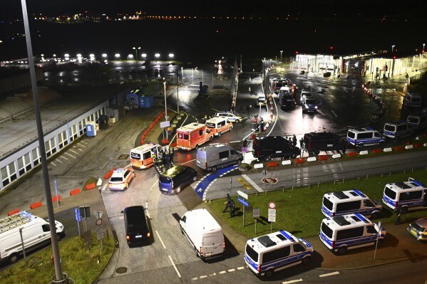 Police vehicles and ambulances arrive at the scene of a security breach at the Hamburg Airport, Saturday, Nov. 4, 2023, in Hamburg, Germany. The airport was closed to passengers, and flights were canceled Saturday night after a vehicle broke through security and entered the premises, German news agency dpa reported. (Jonas Walzberg/dpa via AP)