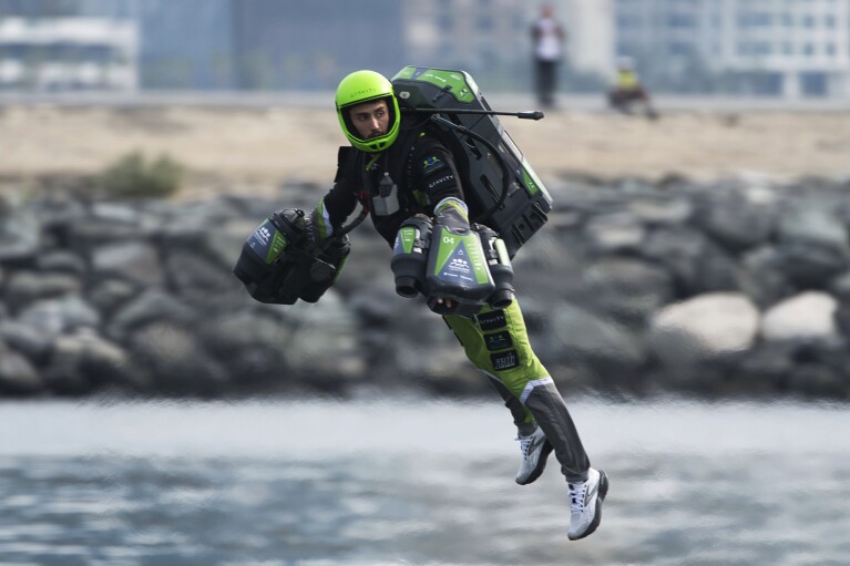 A jet suit pilot races in Dubai, United Arab Emirates, Wednesday, Feb. 28, 2024. Dubai on Wednesday hosted what it called its first-ever jet suit race. Racers zipped along a route with the skyscrapers of Dubai Marina looming behind them, controlling the jet engines on their hands and their backs. (AP Photo/Jon Gambrell)