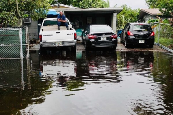 A man sits in the bed of a truck as flooding is seen in the Melrose Manors neighborhood west of downtown Fort Lauderdale on Monday, Nov. 9, 2020. Tropical Storm Eta brought heavy rain and high winds to South Florida as it made landfall in the Florida Keys Sunday. (Joe Cavaretta/South Florida Sun-Sentinel via AP)