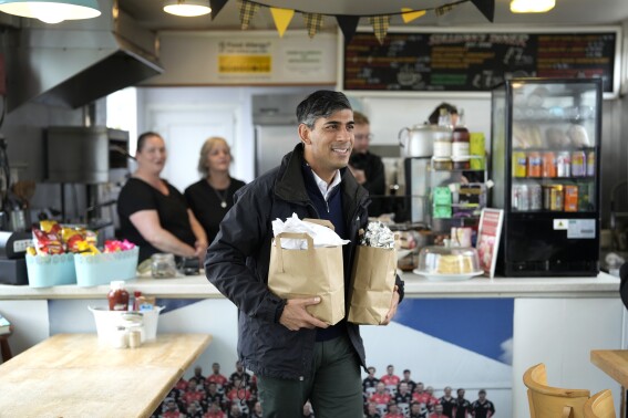 Britain's Prime Minister Rishi Sunak buys breakfast for the travelling media as he arrives at a railway station for a Conservative general election campaign event in the South West of England, Wednesday, May 29, 2024. (AP Photo/Alastair Grant, Pool)