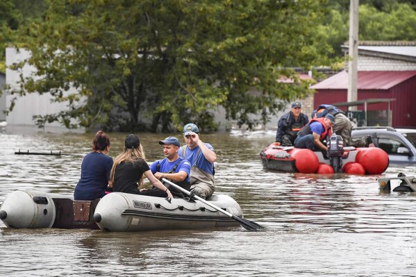 In this photo released by Russian Emergency Ministry Press Service on Sunday, Aug. 13, 2023, Emergency service workers give assistance in a flooded village in Primorye region, Russia's Far East after heavy downpours flooded villages in the region in the aftermath of Typhoon Khanun. Russian emergency officials say over 2,000 people have been evacuated from flooded areas of the Primorye region in the country's Far East. (Russian Emergency Ministry Press Service via AP)