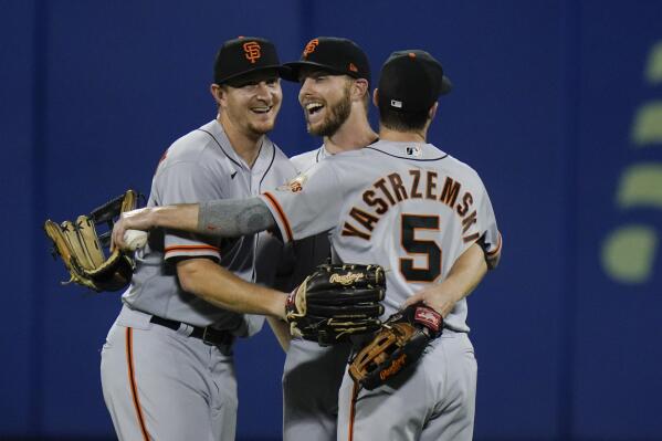 San Francisco Giants' Mike Yastrzemski, right, hugs Alex Dickerson, left, and Austin Slater after a baseball game against the New York Mets Thursday, Aug. 26, 2021, in New York. The Giants won 3-2. (AP Photo/Frank Franklin II)