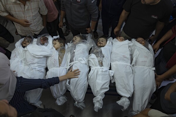 EDS NOTE: GRAPHIC CONTENT - Palestinians stand around the bodies of children killed in Israeli bombardment of the Gaza Strip in a morgue in Khan Younis, Thursday, Oct. 19, 2023. (AP Photo/Fatima Shbair)