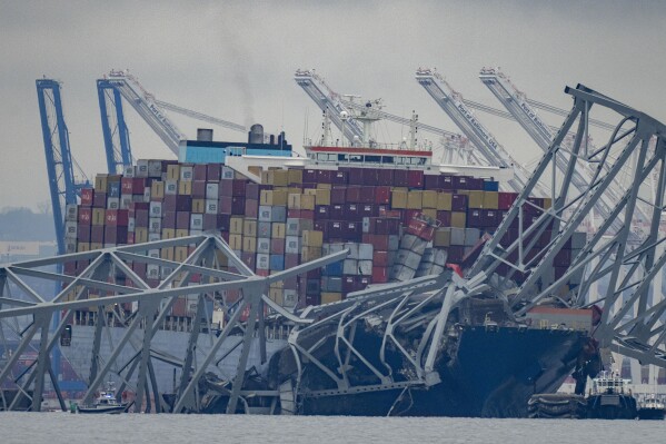 The container ship Dali, owned by Grace Ocean PTE, rests against wreckage of the Francis Scott Key Bridge in the Patapsco River on Wednesday, March 27, 2024, as seen from Pasadena, Md. Investigators began collecting evidence Wednesday from the cargo ship that plowed into Baltimore’s Francis Scott Key Bridge and caused its collapse, while in the waters below divers searched through twisted metal for several construction workers who plunged into the harbor and were feared dead. (AP Photo/Alex Brandon)