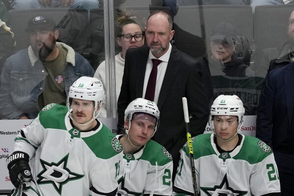Dallas Stars coach Peter DeBoer stands behind center Sam Steel (18), center Roope Hintz (24) and left wing Jason Robertson (21) during the third period of the team's NHL hockey game against the San Jose Sharks in San Jose, Calif., Tuesday, March 26, 2024. (AP Photo/Jeff Chiu)
