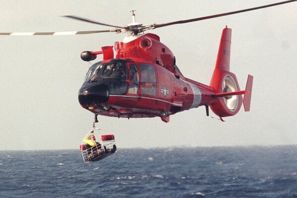 FILE - Balloonist Steve Fossett is retrieved by a U.S. Coast Guard helicopter from waters 10-15 miles north of the island of Oahu in the Hawaiian Islands, Dec. 25, 1998, after abandoning his quest along with Per Lindstrand, of Sweden, and British mogul Richard Branson, who were attempting to make the first nonstop round-the-world flight in a balloon. The massive hunt for the Titan submersible that imploded deep in the North Atlantic has refocused attention on whether wealthy risktakers should pay for emergency search and rescue efforts. (Richard Ambo/Honolulu Star-Advertiser via AP, File)