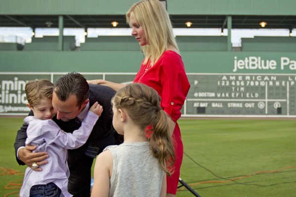 FILE - Boston Red Sox pitcher Tim Wakefield, center left, hugs his son, Trevor, 7, as his wife, Stacy, right, and daughter, Brianna, 6, look on after Wakefield announced his retirement from baseball during a news conference, Friday, Feb. 17, 2012, in Fort Myers, Fla. Stacy Wakefield, the widow of former Boston Red Sox pitcher and two-time World Series champion Tim Wakefield, has died. Wakefield's family said in a statement released through the Red Sox that she died Wednesday, Feb. 28, 2024 at her Massachusetts home, less than five months after her husband died at the age of 57. (AP Photo/David Goldman, File)