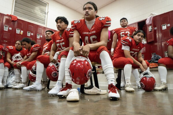 Lahainaluna High School football team players listens to co-head coach Dean Rickard before their homecoming game at Sue D. Cooley Stadium, Saturday, Oct. 21, 2023, in Lahaina, Hawaii. (AP Photo/Mengshin Lin)