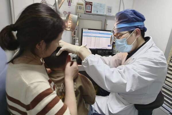 In this photo provided by researchers in January 2024, Dr. Yilai Shu examines a young patient at the Eye & ENT Hospital of Fudan University in Shanghai, China, after a gene therapy procedure for hereditary deafness. A small study published Wednesday, Jan. 25, 2024, in the journal Lancet, documents significantly restored hearing in five of six kids treated in China. (Courtesy Dr. Yilai Shu via AP)