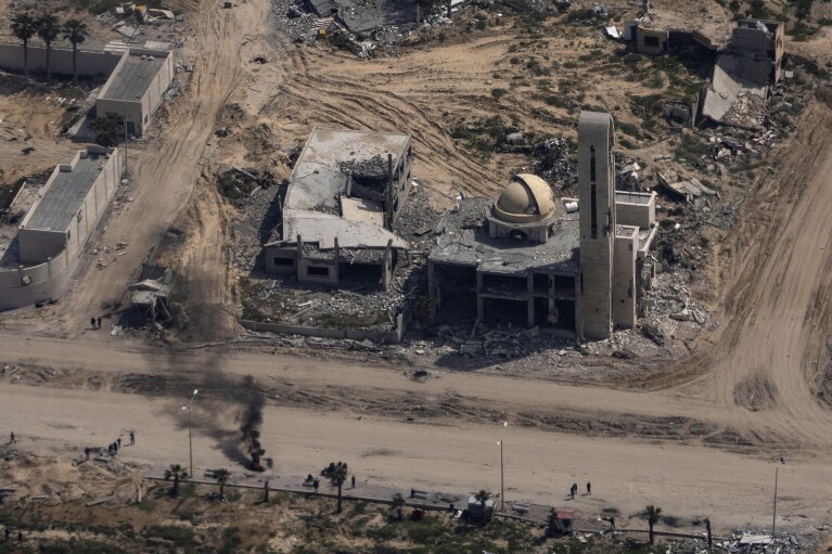 Destroyed buildings are seen through a window of an airplane from the U.S. Air force overflying the Gaza Strip, Thursday, March 14, 2024. (AP Photo/Leo Correa)