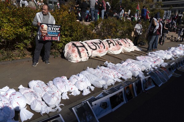 Protesters place white sacks representing the bodies of people killed in Gaza during a pro-Palestinian demonstration at Freedom Plaza in Washington, Saturday, Nov. 4, 2023.(AP Photo/Jose Luis Magana)