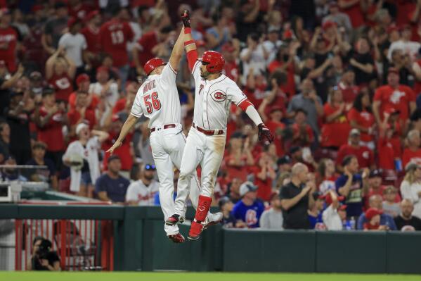 Cincinnati Reds' Eugenio Suarez, right, leaps to high-five J.R. House after hitting a solo home run during the seventh inning of a baseball game against the Atlanta Braves in Cincinnati, Friday, June 25, 2021. (AP Photo/Aaron Doster)