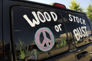 FILE - This Aug. 14, 2009 file photo shows a van decorated with "Woodstock or Bust" at the original Woodstock Festival site in Bethel, N.Y.   Woodstock 50 is officially cancelled. Organizers announced Wednesday, July 31, 2019 that the troubled festival that hit a series of setbacks in the last four months won’t take place next month. The three-day festival was originally scheduled for Aug. 16-18, but holdups included permit denials and the loss of a financial partner and a production company.(AP Photo/Stephen Chernin, File)