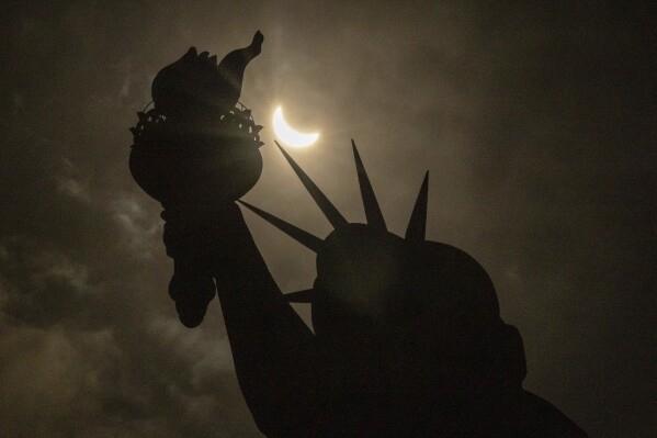 The moon partially covers the sun behind the Statue of Liberty during the total solar eclipse on the Liberty Island, Monday, April. 8, 2024, in New York. (AP Photo/Yuki Iwamura)