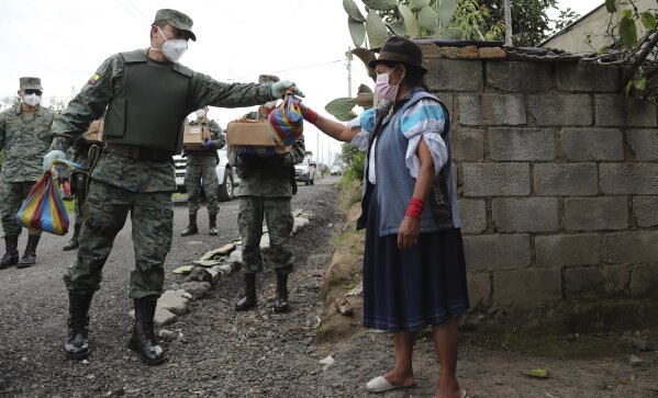 Soldiers deliver food to a woman who cannot leave her house because of the government's request that people don't leave their homes to prevent the coronavirus from spreading throughout the city in Zambiza, near Quito, Ecuador, Thursday, April 2, 2020. The government has declared a "health emergency," restricting movement to only those who provide basic services, enacting a curfew, and closing schools. (AP Photo/Dolores Ochoa)