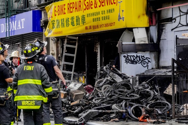 Firefighters and investigators go through the aftermath of a fire which authorities say started at an e-bike shop and spread to upper-floor apartments, Tuesday, June 20, 2023, in New York. (AP Photo/Bebeto Matthews)
