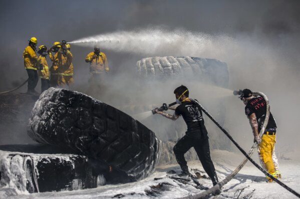 
              Israeli firefighters extinguish tractor tires in a farmland set on fire by a kite with attached burning cloth launched from Gaza on the Israeli side of the border, Tuesday, May 15, 2018. Israel faced a growing backlash Tuesday and new charges of using excessive force, a day after Israeli troops firing from across a border fence killed dozens of Palestinians and wounded more than 2,700 at a mass protest in Gaza. (AP Photo/Tsafrir Abayov)
            