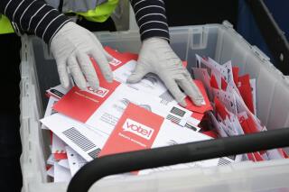 FILE - In this March 10, 2020, file photo wearing gloves, a King County Election worker collect ballots from a drop box in the Washington State primary, in Seattle. But the 2020 presidential election is creeping ever closer, and there are no signs yet of pandemic abating, nor any word on when Americans on orders to stay home can resume normal life, and so lawmakers are trying to figure how to allow for voting in a world where face-to-face contact causes anxiety at the least, and sickness and death at the most. (AP Photo/John Froschauer, File)