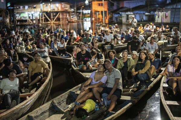 Spectators watch a film from boats during the Muyuna Floating Film Festival, showcasing films from countries with tropical forests, in the Belen neighborhood of Iquitos, Peru, on Sunday, May 26, 2024. (AP Photo/Rodrigo Abd)