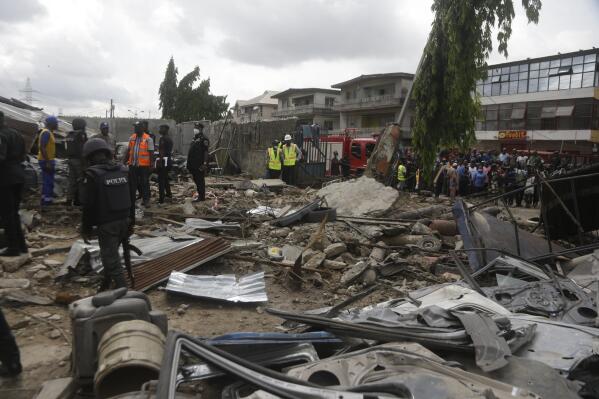 Police officers inspect the scene of a gas explosion in Lagos, Nigeria, Tuesday, Nov. 16, 2021. Emergency service officials in Nigeria say that a gas explosion in Lagos has killed at least five people, including a child. The gas explosion occurred on Tuesday morning in a crowded area of Lagos. (AP Photo/Sunday Alamba)