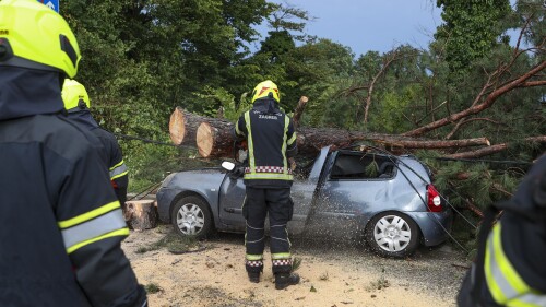 Firefighters remove fallen tree branches from damaged parked car after a powerful storm, in Zagreb, Croatia, Wednesday, July 19, 2023. A powerful storm with strong winds and heavy rain hit Croatia and Slovenia on Wednesday, killing at least three people and injuring several others. (AP Photo)