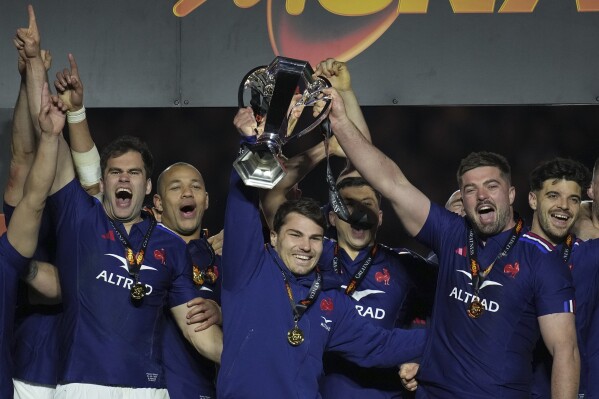 FILE -The French team players Antoine Dupont, center, and Gregory Alldritt, right, celebrate with the trophy after the Six Nations rugby union match between France and Scotland at the Stade de France in Saint-Denis, outside Paris, March 15, 2025. (AP Photo/Christophe Ena, File)