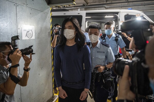Police officers escort Tsang Chi-kin off a police van at the district court on July 14, 2022 in Hong Kong. The Hong Kong man who was shot by police during pro-democracy protests in 2019 has been sentenced Wednesday, Oct. 18, 2023, to 47 months in prison on charges of rioting, assaulting a police officer and perverting the course of justice. Tsang Chi-kin was the first known victim of police gunfire during the months-long protests. (AP Photo/Vernon Yuen)