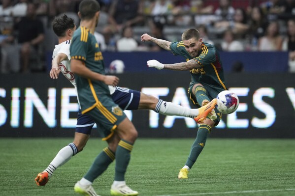 Los Angeles Galaxy's Tyler Boyd, right, shoots past Vancouver Whitecaps' Alessandro Schopf, back left, during the second half of an MLS soccer match Saturday, July 15, 2023, in Vancouver, British Columbia. (Darryl Dyck/The Canadian Press via AP)