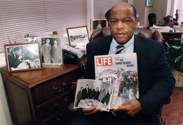 Congressman John Lewis is seen in his Atlanta office with two of his favorite items from his collection of memorabilia from his younger days as a civil rights activist in the 1960s. He is holding a Life Magazine cover picturing the famous Selma march in 1965. (He is in this photo at front of the line of marchers.) He is also holding a photo of the 'Big Six' civil rights leaders of the time to plan for the famous March on Washington. The men in the photo are L to R: John Lewis, Whitney Young, A. Phillip Randolph, Martin Luther King, James Farmer, and Roy Wilkins. In background photos (picture at left) of Dr. Martin Luther King with Fred Shuttlesworth and Ralph Abernathy and Lewis with Robert Kennedy (picture at right)." (Atlanta Journal-Constitution via AP)