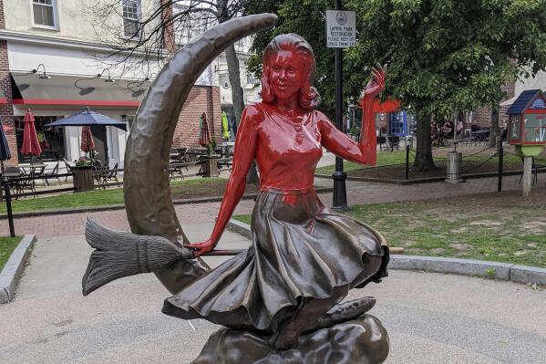 This image provided by Daniel Fury shows the "Bewitched" statue partially covered with red paint, Monday, June 6, 2022, in Salem, Mass. Witnesses called police Monday to report someone spray painting the bronze statue, police said. The statue depicts actor Elizabeth Montgomery as lead character Samantha Stephens in the 1960s sitcom sitting on a broomstick in front of a crescent moon. (Daniel Fury/Black Cat Tours via AP)