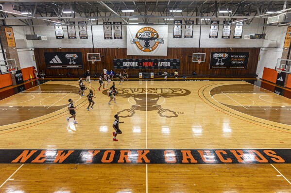 Players on the New York Gauchos boy's basketball team warm up before practice at the Gaucho Gym, Monday, March 11, 2024, in the Bronx borough of New York. Book Richardson doesn’t sleep much past 5:30 a.m. anymore. That was around the time seven years ago that FBI agents pounded on his door, barged in, handcuffed him and dragged him away while his 16-year-old son, E.J., looked on helplessly. These days, Richardson runs the boys’ basketball program for the New York Gauchos, a venerated hoops proving ground based in a gym near the 149th St-Grand Concourse subway stop in the Bronx. (AP Photo/Peter K. Afriyie)