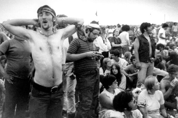 FILE - In this Aug. 16, 1969, file photo, rock music fans relax during a break in the entertainment at the Woodstock Music and Arts Fair in Bethel, N.Y. Timing alone ensures that the Woodstock music festival and Charles Manson murders will be joined in memory. But the apex of peace and love and the abyss of pitiless violence were born out of similar drives as old as the U.S. itself. (AP Photo/File)