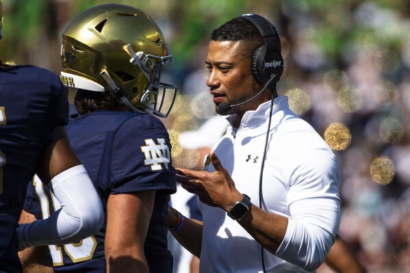 Notre Dame head coach Marcus Freeman, right, talks with quarterback Sam Hartman, left, during the first half of an NCAA college football game on Saturday, Sept. 2, 2023 in South Bend, Ind. (AP Photo/Michael Caterina)