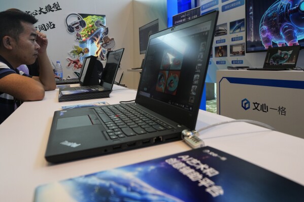 A visitor checks out the AI chatbot Ernie Bot via a laptop computer at a booth promoting the AI chatbot during the Wave Summit in Beijing on Aug. 16, 2023. Chinese search engine and artificial intelligence firm Baidu on Thursday made its ChatGPT-equivalent language model available to the public, in a sign of a green light from Beijing which has in recent months taken steps to regulate the industry. (AP Photo/Andy Wong)