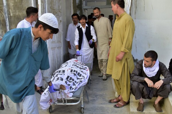 Hospital staff and relatives transport the body of a police officer at a hospital, in Quetta, Pakistan Tuesday, Aug. 1, 2023. Gunmen on motorcycles opened fire on police escorting a team of polio workers on Tuesday during a door-to-door vaccination campaign in the southwest, killing two police officers before fleeing, police said. (AP Photo/Arshad Butt)