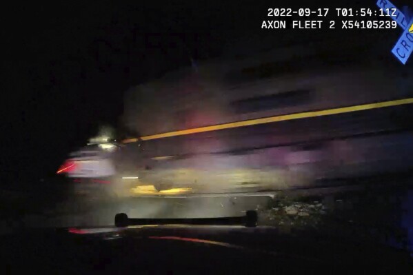 This screen grab from dash camera video provided by the Fort Lupton Police Department shows a freight train hitting a parked police car with a suspect inside, Sept. 16, 2022, in Fort Lupton, Colo. A trial began Monday, July 24, 2023, for the police officer accused of putting the handcuffed woman in the car. The collision seriously injured 21-year-old Yareni Rios. The date/time stamp shown on the video is incorrect. (Fort Lupton Police Department via AP)