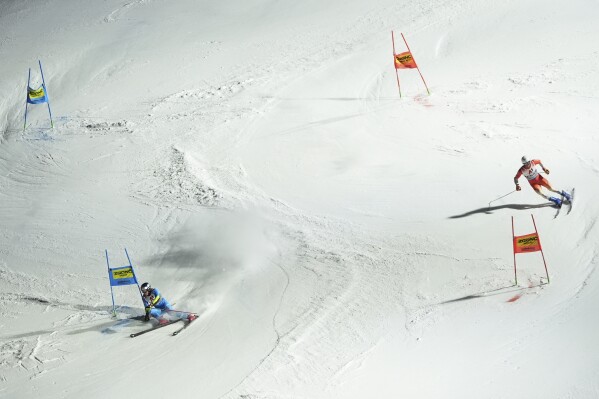 Italy's Alex Vinatzer, left, and Switzerland's Thomas Tumler compete during the final of the alpine ski, World Championship team parallel event, in Saalbach-Hinterglemm, Austria, Tuesday, Feb. 4, 2025. (AP Photo/Giovanni Auletta)