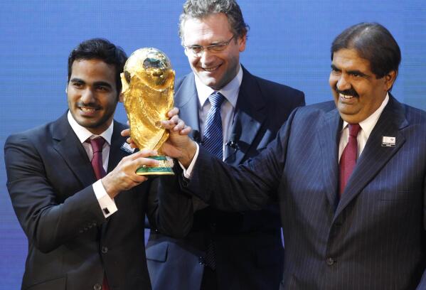 FILE - Mohamed bin Hamad Al-Thani, left, Chairman of the 2022 bid committee, and Sheikh Hamad bin Khalifa Al-Thani, Emir of Qatar, hold the World Cup trophy in front of FIFA Secretary General Jerome Valcke after the announcement that Qatar will host the 2022 soccer World Cup, on Dec. 2, 2010, in Zurich, Switzerland. Qatar has for years employed a former CIA officer to help spy on soccer officials as part of an aggressive effort to win and hold on to the 2022 World Cup tournament, an investigation by The Associated Press has found. (AP Photo/Anja Niedringhaus, File)