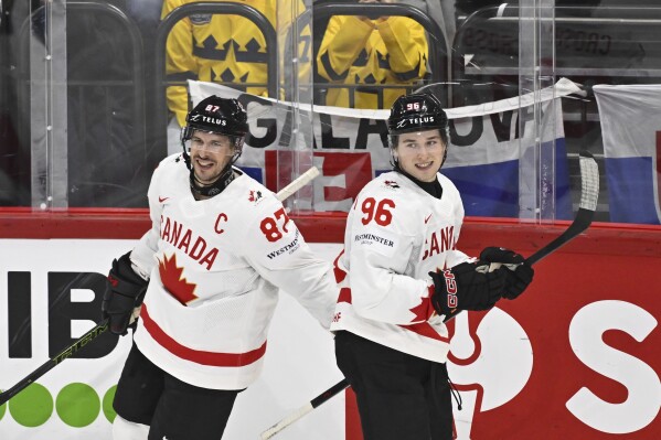 Canada's Sidney Crosby, left, celebrates Macklin Celebrini after scoring a goal during a Group A match between Canada and Slovakia at the hockey world championships, Saturday, May 17, 2025, at Avicii Arena in Stockholm, Sweden (Anders Wiklund/TT News Agency via AP)