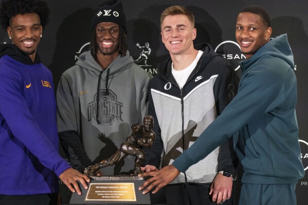 Heisman Trophy finalists, from left, LSU quarterback Jayden Daniels, Ohio State wide receiver Marvin Harrison Jr., Oregon quarterback Bo Nix and Washington quarterback Michael Penix Jr. pose for a photo with the Heisman Trophy, Friday, Dec. 8, 2023, in New York. The Heisman Trophy will be announced Saturday, Dec. 9. (AP Photo/Eduardo Munoz Alvarez)