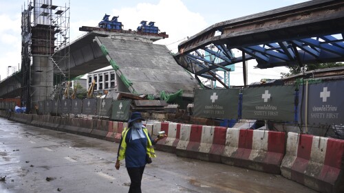 A worker walks past a collapsed elevated road in Bangkok, Tuesday, July 11, 2023. At least one person was killed after the elevated road in Thailand’s capital collapsed, and a few others were listed as missing, with rescue crews unable to access the site Tuesday for fear of a further collapse, authorities said. (AP Photo/Thanchote Thanawikran)