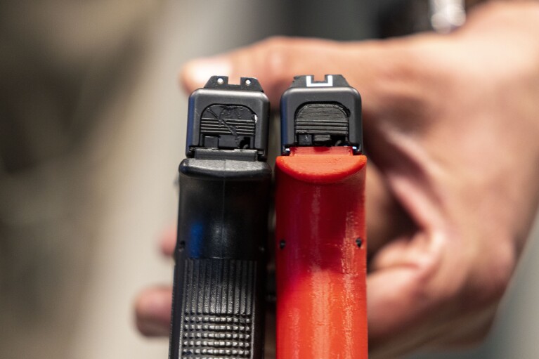 Two semi-automatic pistols are displayed for a photograph, one with a conversion device installed making it fully automatic, at the Bureau of Alcohol, Tobacco, Firearms, and Explosives (ATF), National Services Center, Thursday, March 2, 2023, in Martinsburg, W.Va. Machine guns have been illegal in the U.S. for decades, but in recent years the country has seen a new surge of weapons capable of automatic fire. Small pieces of plastic or metal used to convert legal guns into homemade machine guns are helping to fuel gun violence. (AP Photo/Alex Brandon)