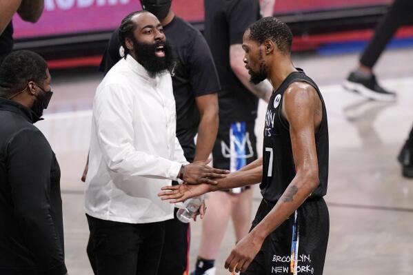 Injured Brooklyn Nets player James Harden, center left, greets Nets forward Kevin Durant (7) at the end of the third quarter of Game 2 of an NBA basketball second-round playoff series against the Milwaukee Bucks, Monday, June 7, 2021, in New York. (AP Photo/Kathy Willens)