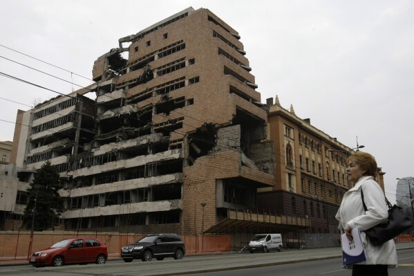 FILE- A woman walks in front of the destroyed former Serbian army headquarters in Belgrade, Serbia, March 24, 2010. Opposition groups in Serbia are planning protests against a real estate development project that will be financed by the firm of Donald Trump's son-in-law, Jared Kushner, at the site of the former Serbian army headquarters destroyed in a U.S.-led NATO bombing campaign in 1999. The Serbian government earlier this week signed a deal with a Kushner-related company for the 99-year lease of land in central Belgrade for the "revitalization" of the bombed-out buildings. (AP Photo/Darko Vojinovic, File)